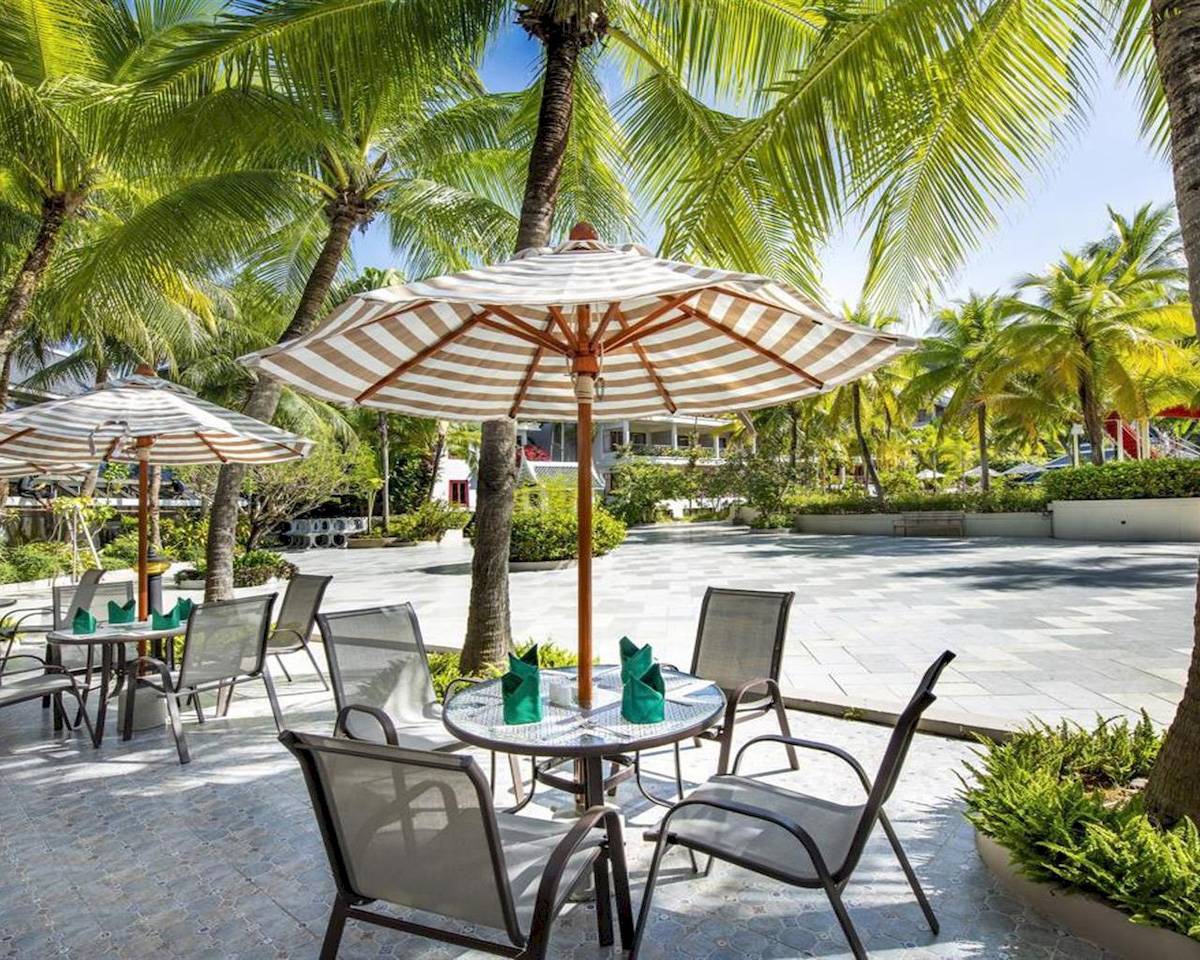 Gartenbereich des Chada Thai Village Resorts mit Tisch, Stühlen und Sonnenschirmen.