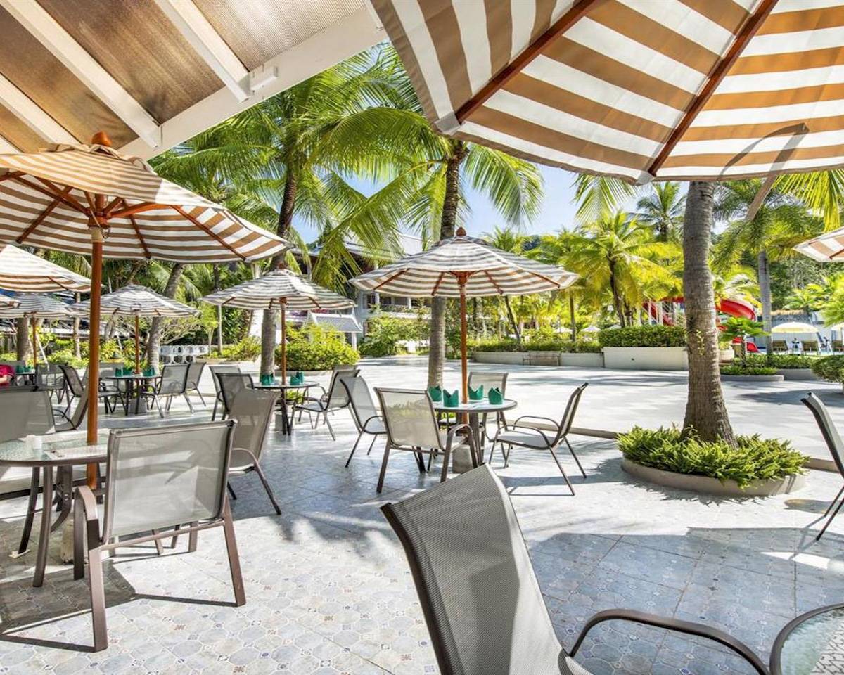 Terrasse des Chada Thai Village Resorts mit gesäumten Tischen und Stühlen.