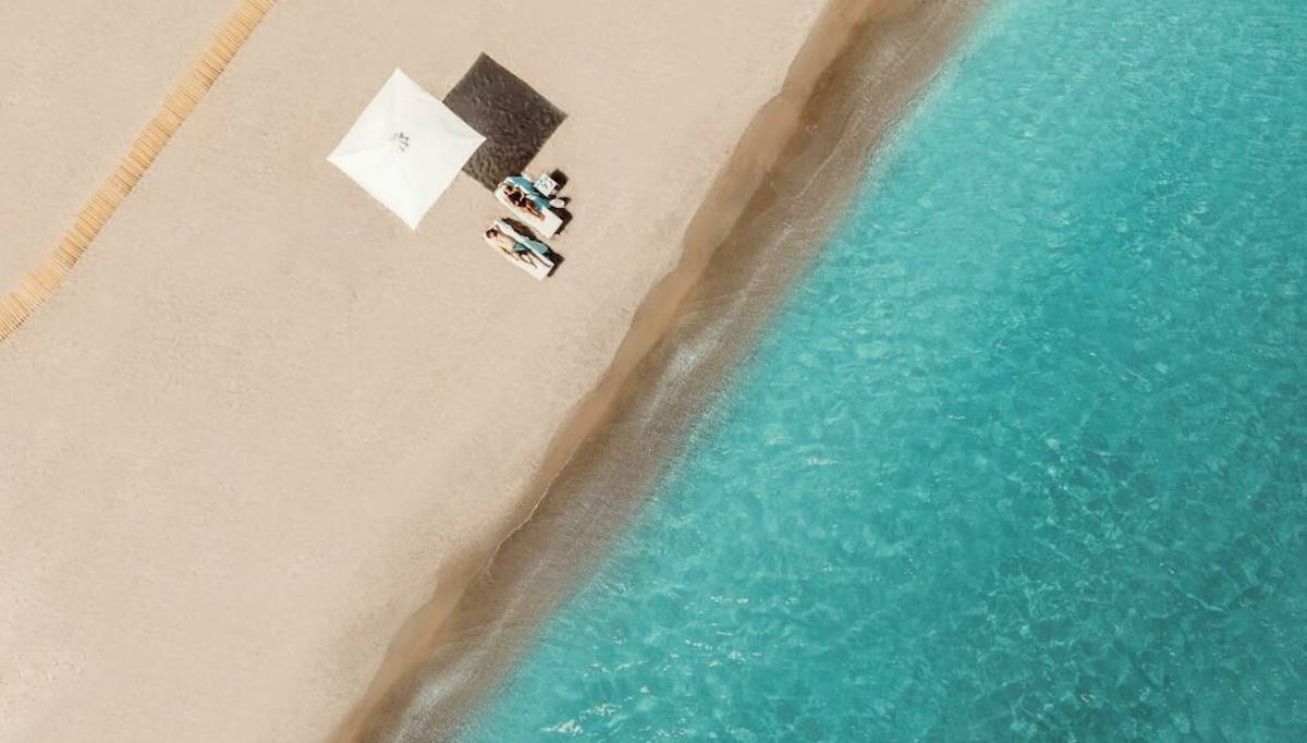 Ikos Aria Strand mit Sonnenliegen und Umbrella