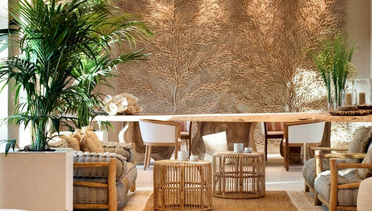 Ein Hotel-Loungebereich mit einem langen Holztisch, umgeben von Stühlen und Pflanzen.