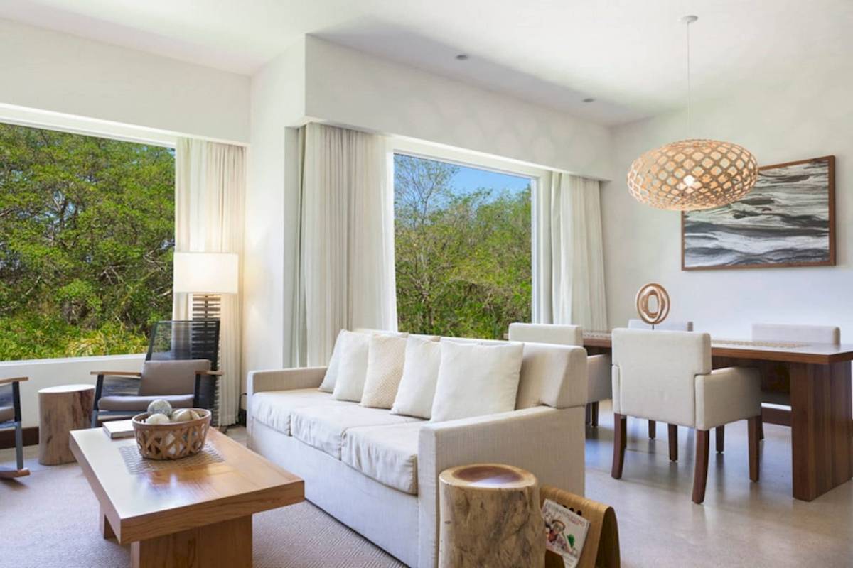 Wohnzimmer im El Mangroove, Autograph Collection mit großem Fenster, weiße Möbel und Ausblick auf Bäume