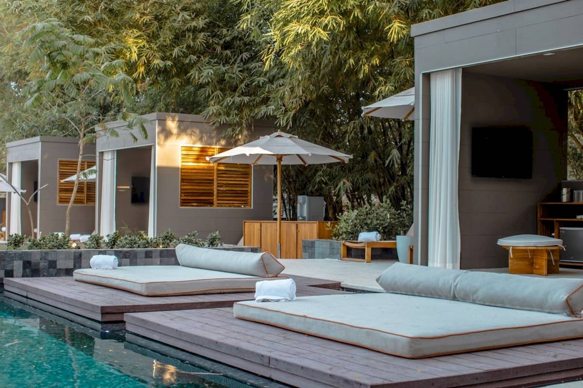 Poolside-Lounge im El Mangroove, Autograph Collection mit zwei Liegen, einem Schirm und einer Hängematte.