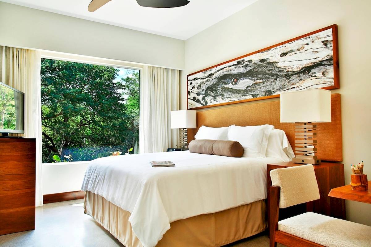 Schlafzimmer im El Mangroove, Autograph Collection Hotel mit großem Bett, Fenster und Dekor.