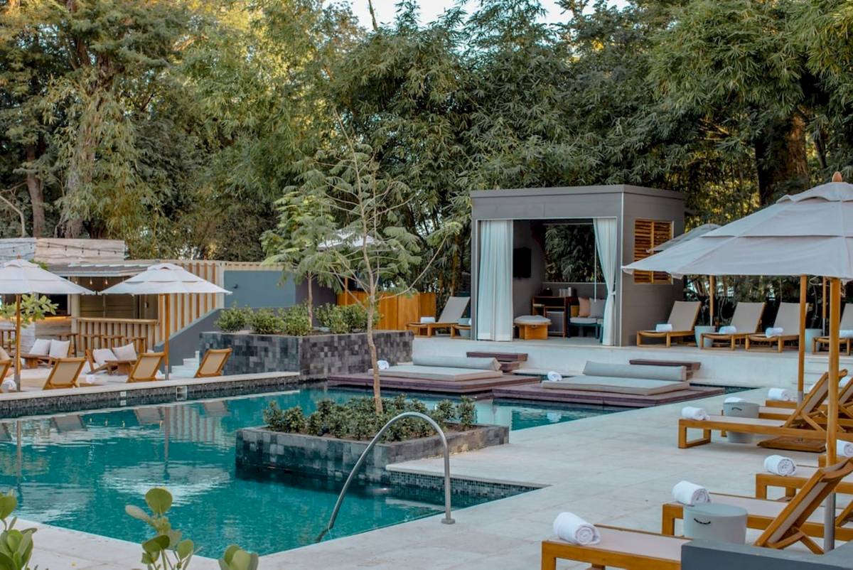 Pool-Terrasse im El Mangroove, Autograph Collection Hotel mit Lounge-Sesseln, Sonnenschirmen und grüner Umgebung.