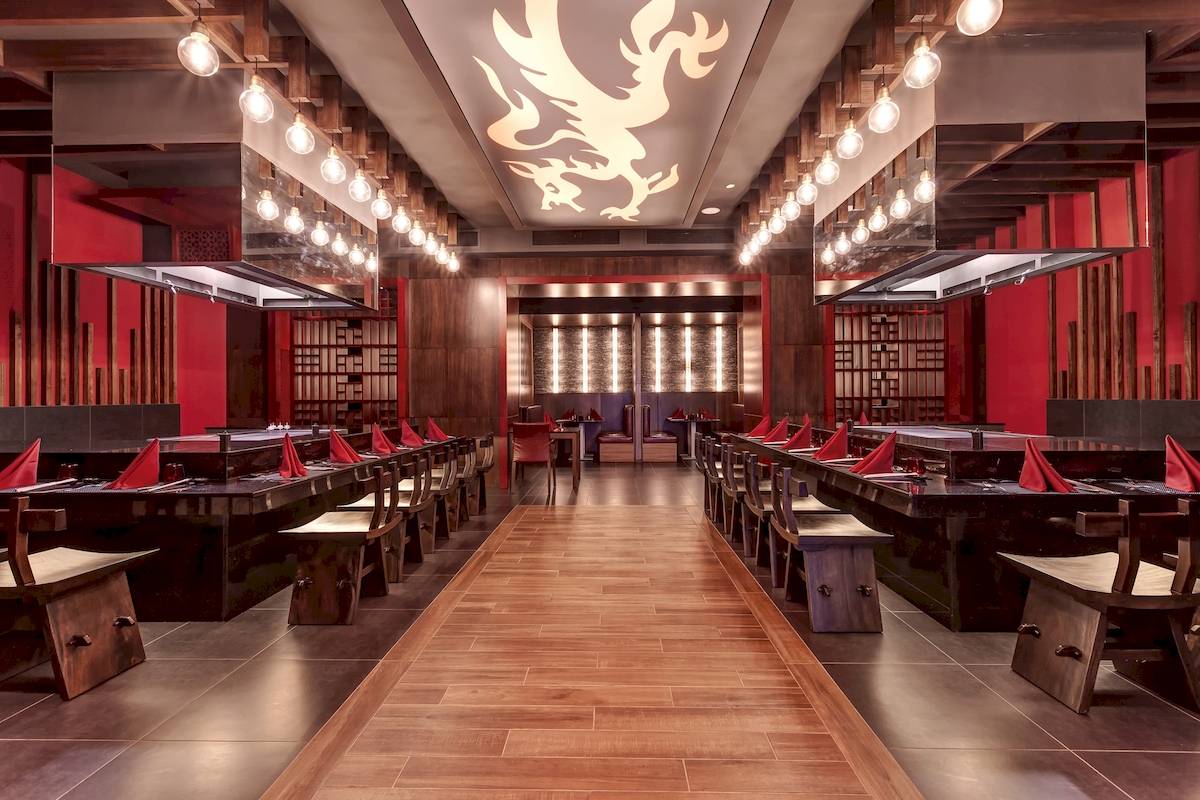 Innenansicht des Restaurants im Planet Hollywood Beach Resort mit roten Wänden, hölzernem Boden und langen Tischen.