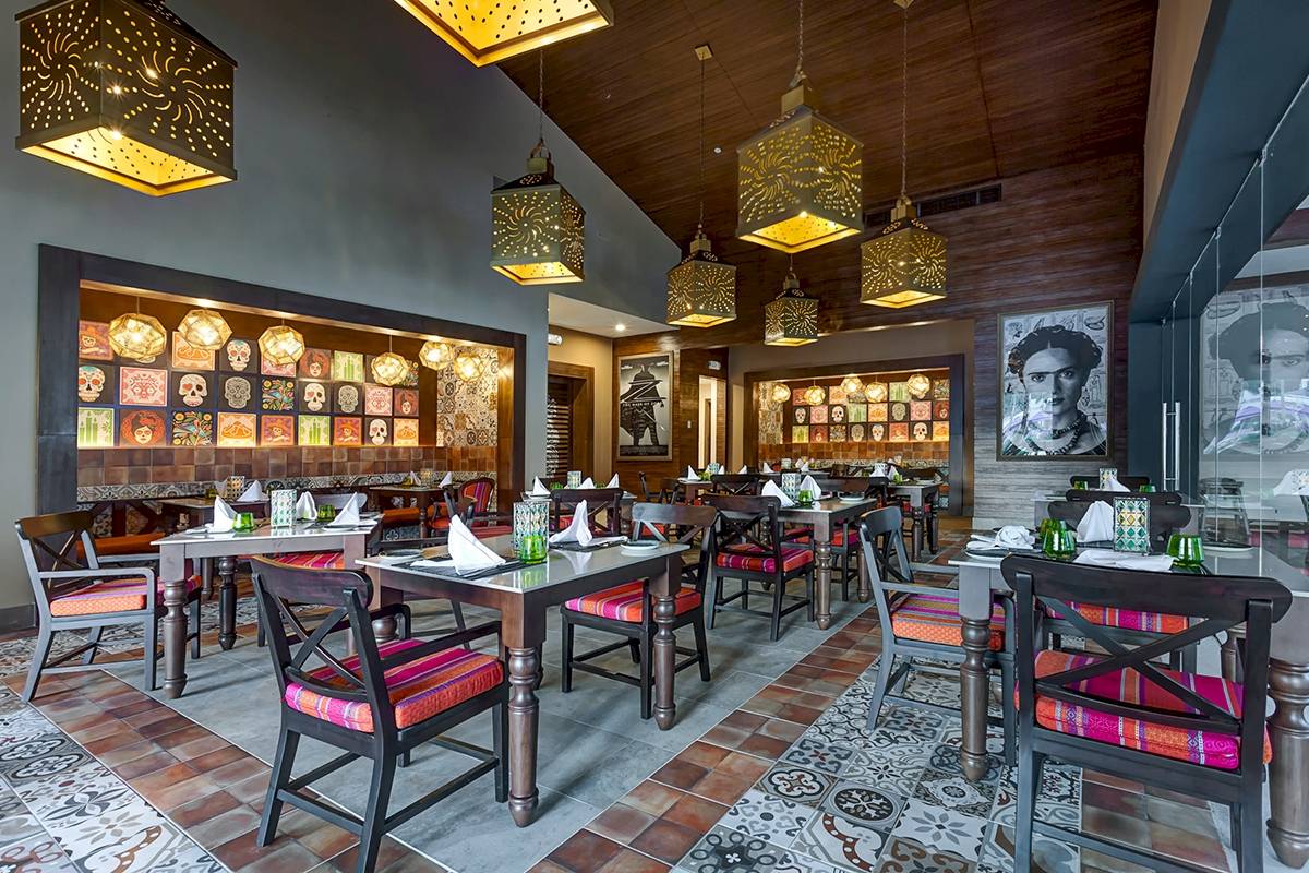 Innenansicht des Restaurants im Planet Hollywood Beach Resort mit farbenfrohen Sitzmöbeln, Holzdecken und kunstvollen Lampen.