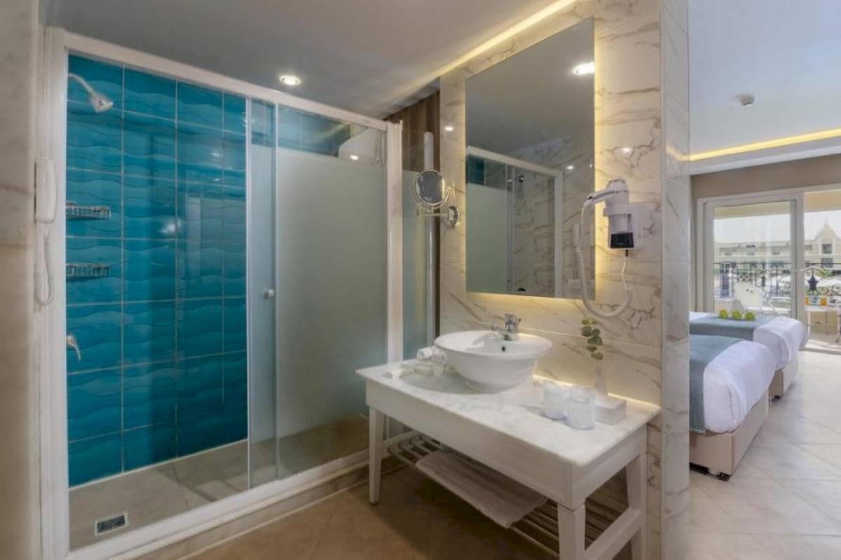Badezimmer im Titanic Royal Hotel mit blauen Fliesen, einer Dusche und einem Waschbecken.