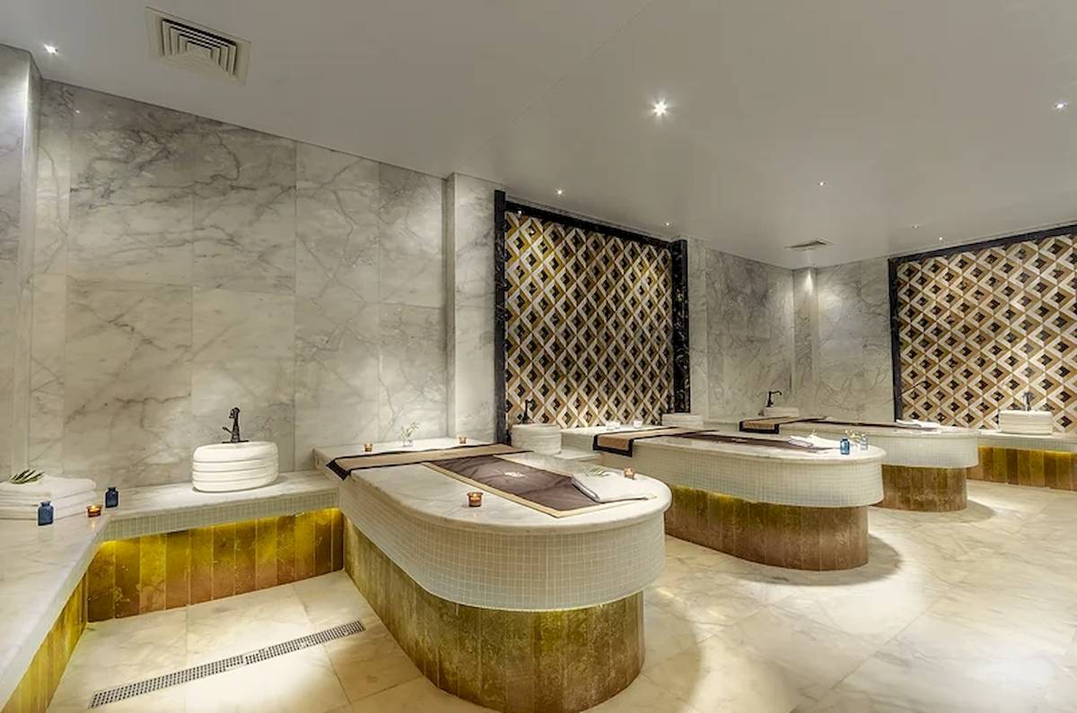 Spa-Behandlungsraum im Titanic Royal Hotel mit Marmorwänden und goldenen Akzenten.