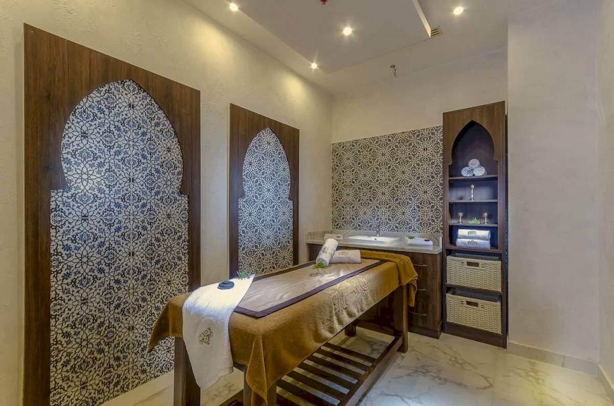Spa-Behandlungsraum im Hotel Titanic Royal mit Holzmöbeln, blau-weißen Wandfliesen und einer Liege.