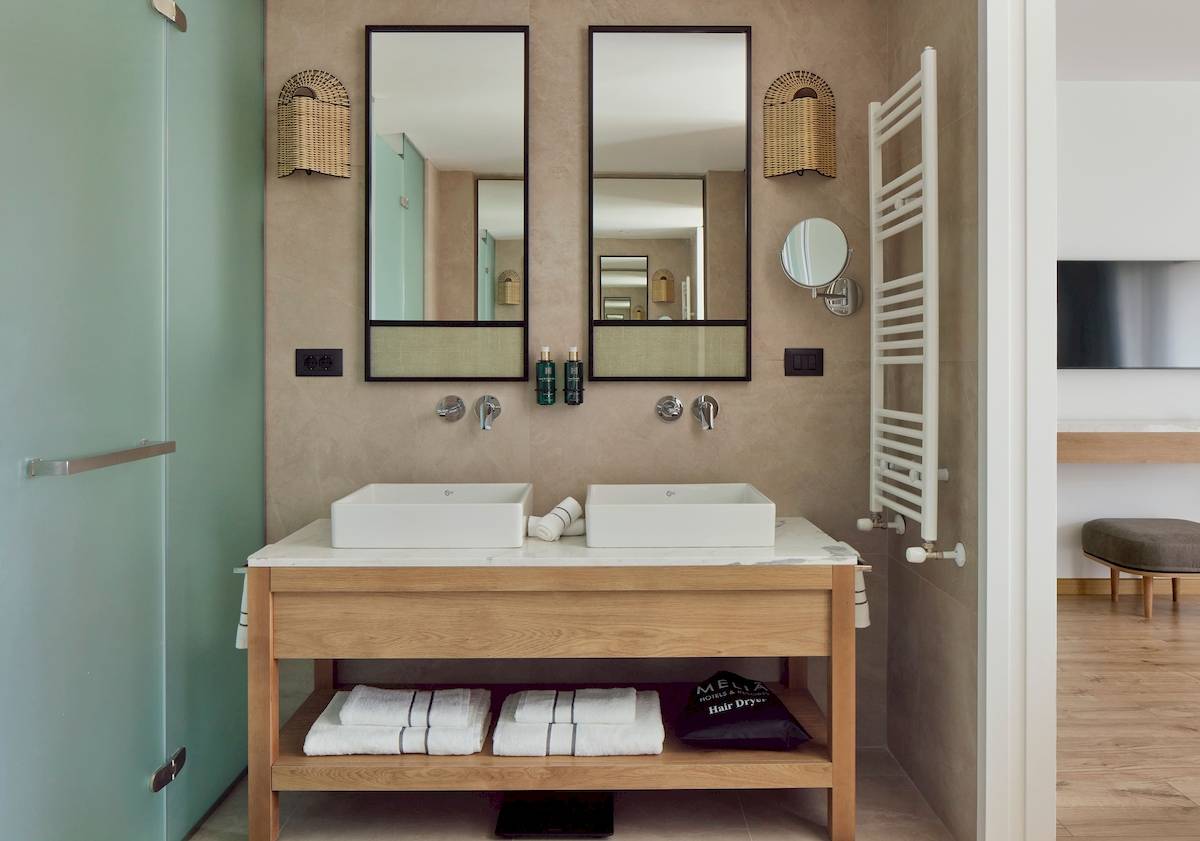 Badezimmer im Melia Durres Albania Hotel mit zwei Waschbecken, Spiegeln und Handtüchern.