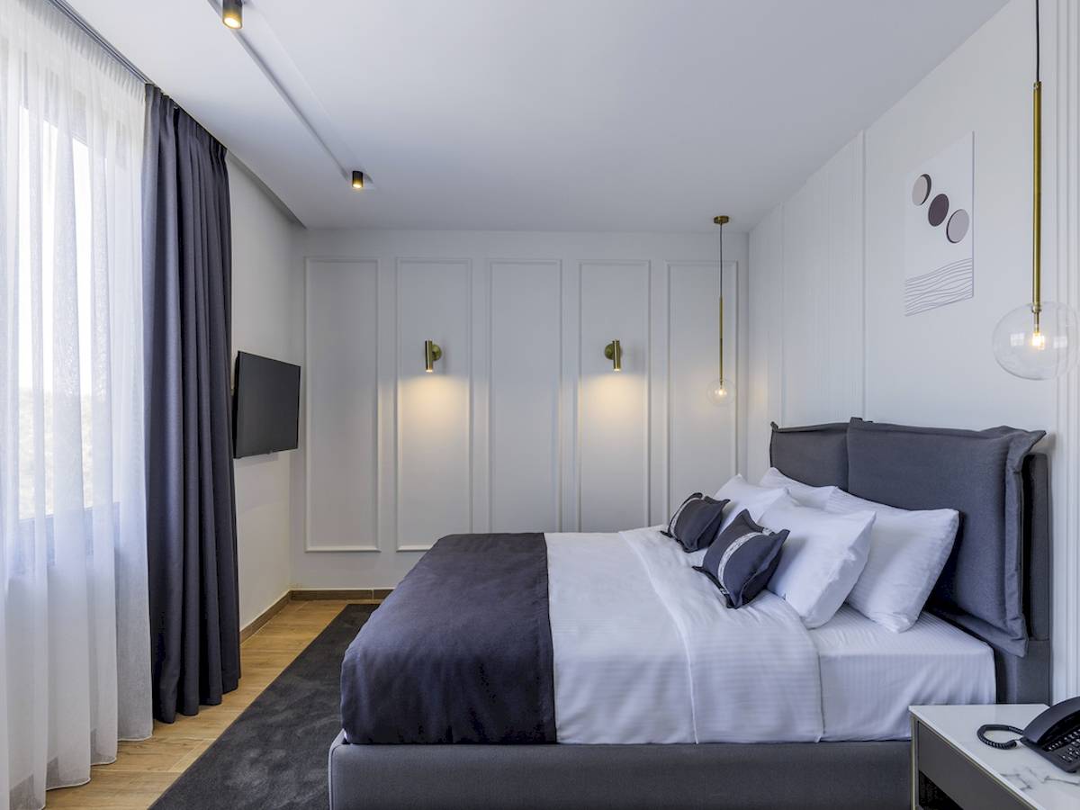 Schlafzimmer im Mövenpick Hotel Lalez Durres mit Bett, Kissen und Fernseher
