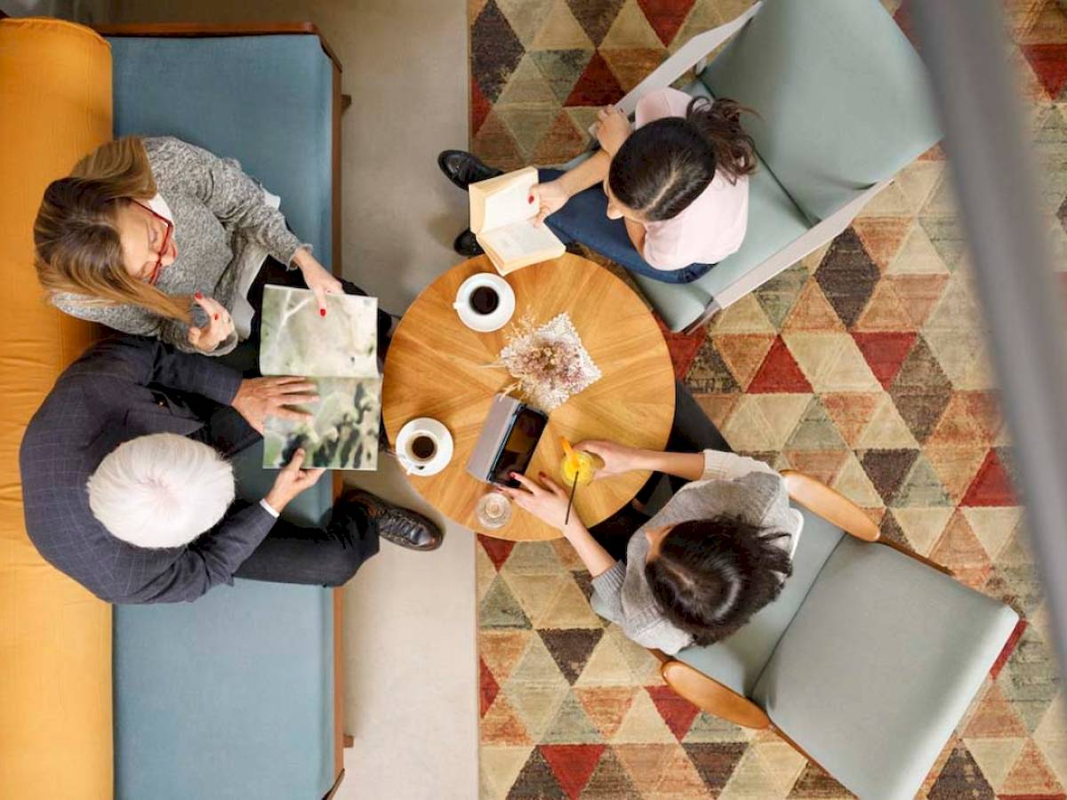 Vier Gäste des Mövenpick Hotel Lalez Durres sitzen in einem modernen Loungebereich und lesen Bücher.