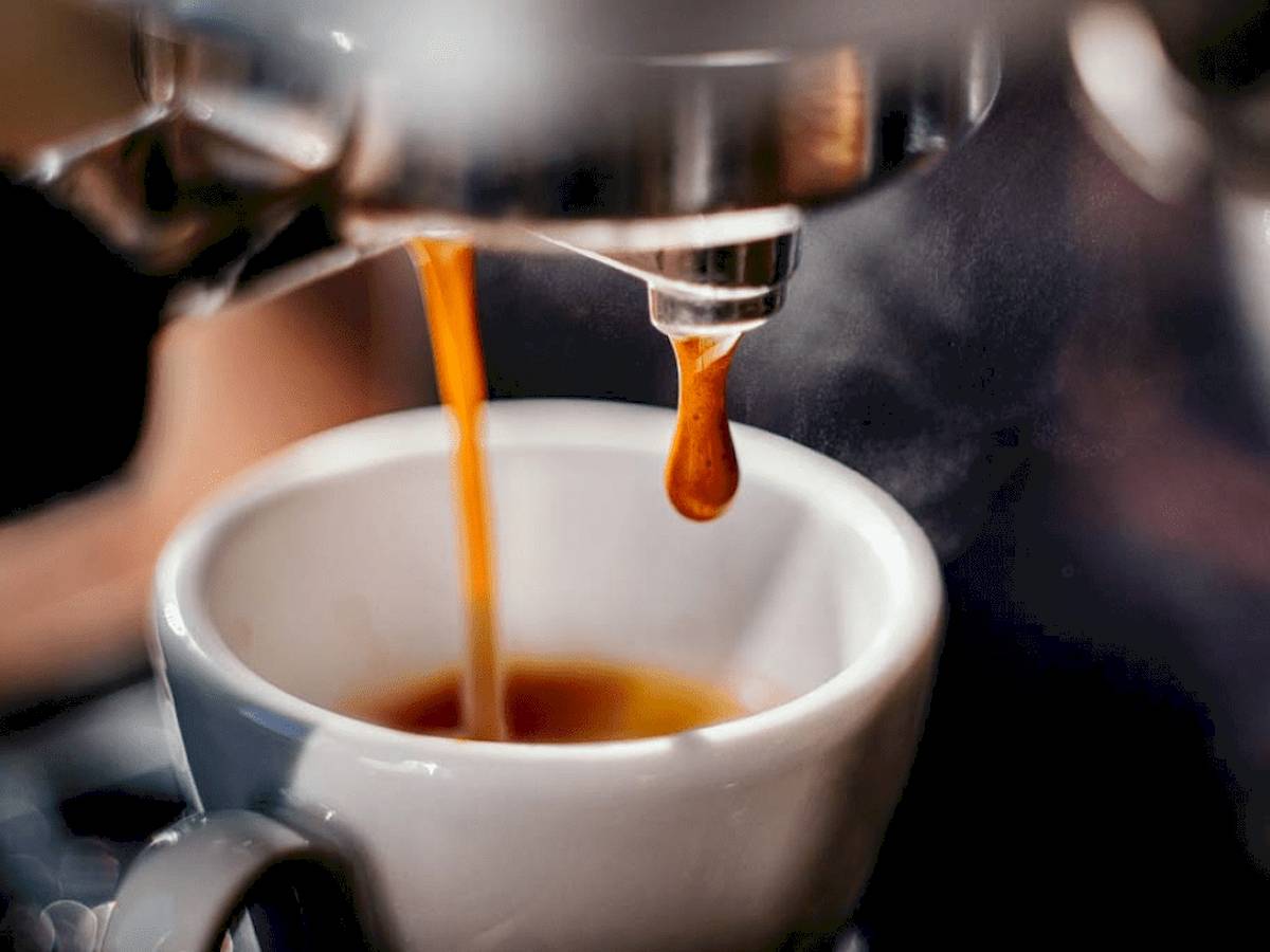Kaffee wird in eine weiße Tasse gebrüht, die auf einem Untersetzer steht.