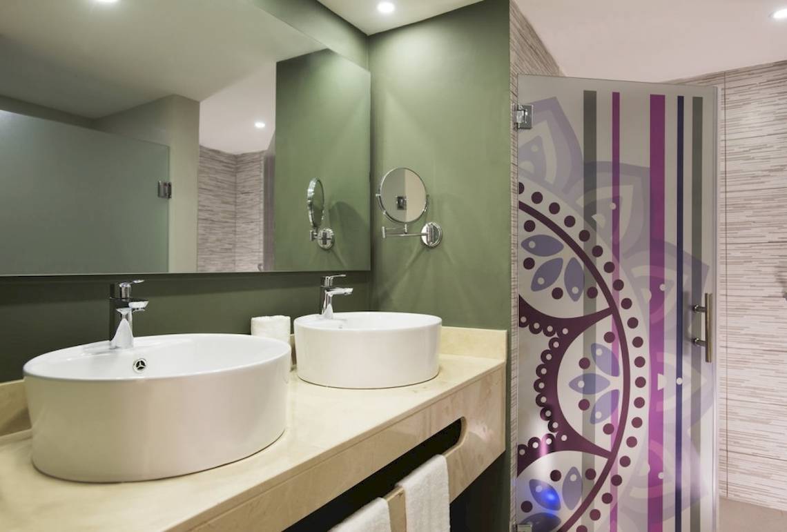 Badezimmer im Emotions By Hodelpa Hotel in Puerto Plata mit zwei Waschbecken und grün gestrichenen Wänden.