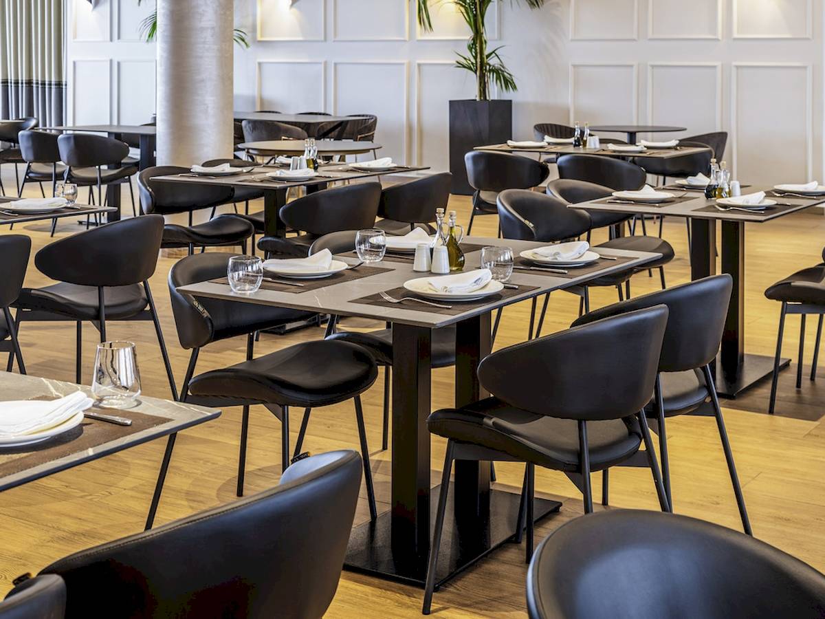 Innenansicht des Restaurants im Mövenpick Hotel Lalez Durres mit gedeckten Tischen und Stühlen.