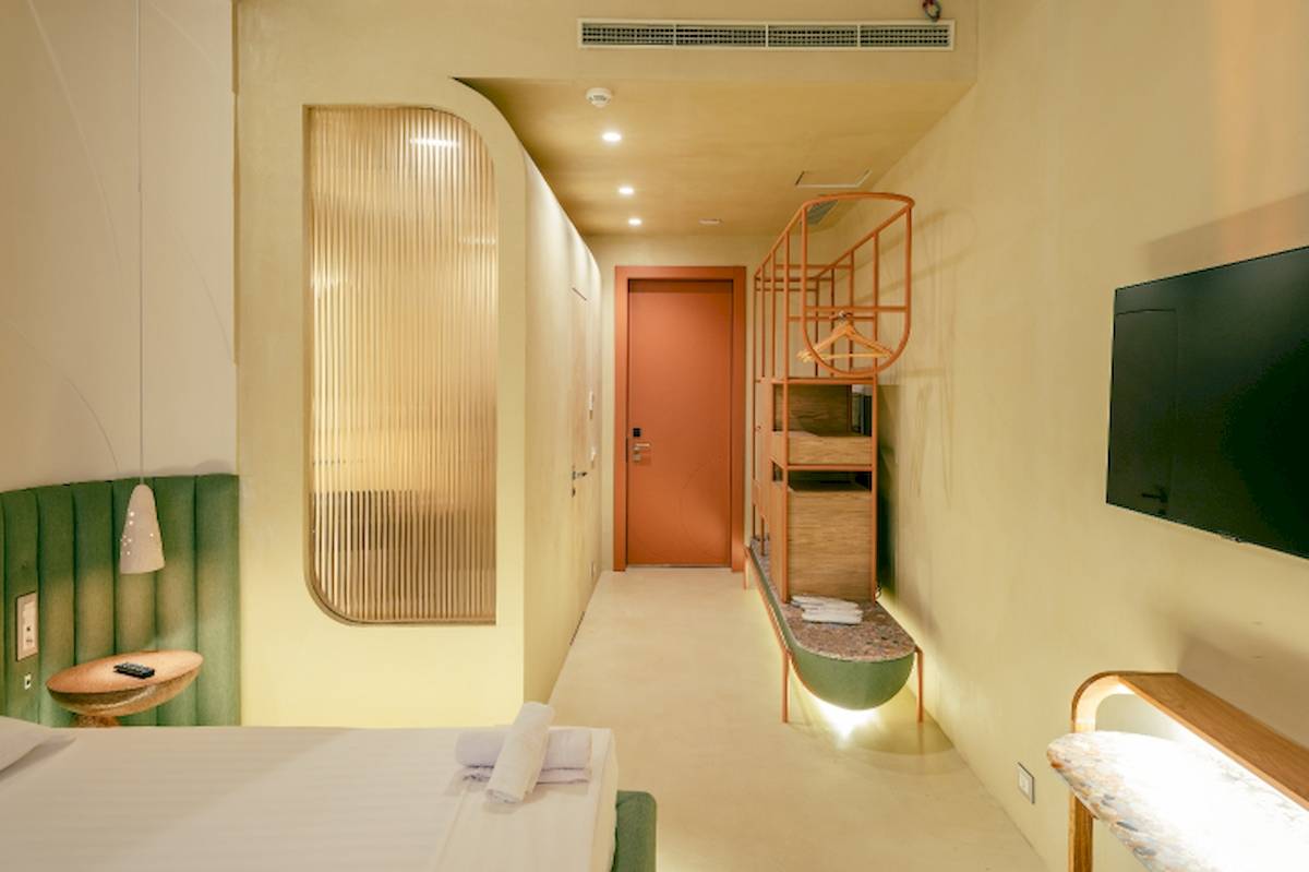 Innenansicht eines Zimmers im Epidamn White Sensation Hotel mit einem Bett, einem Nachttisch und einem Fernseher.