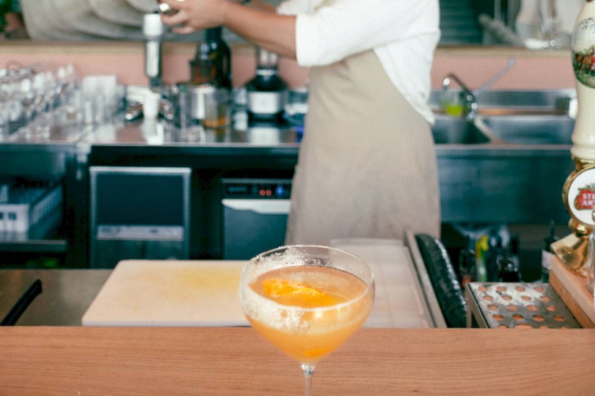Cocktail Bar im Epidamn White Sensation Hotel mit einem fertigen Getränk und einer Person, die einen Cocktail zubereitet.