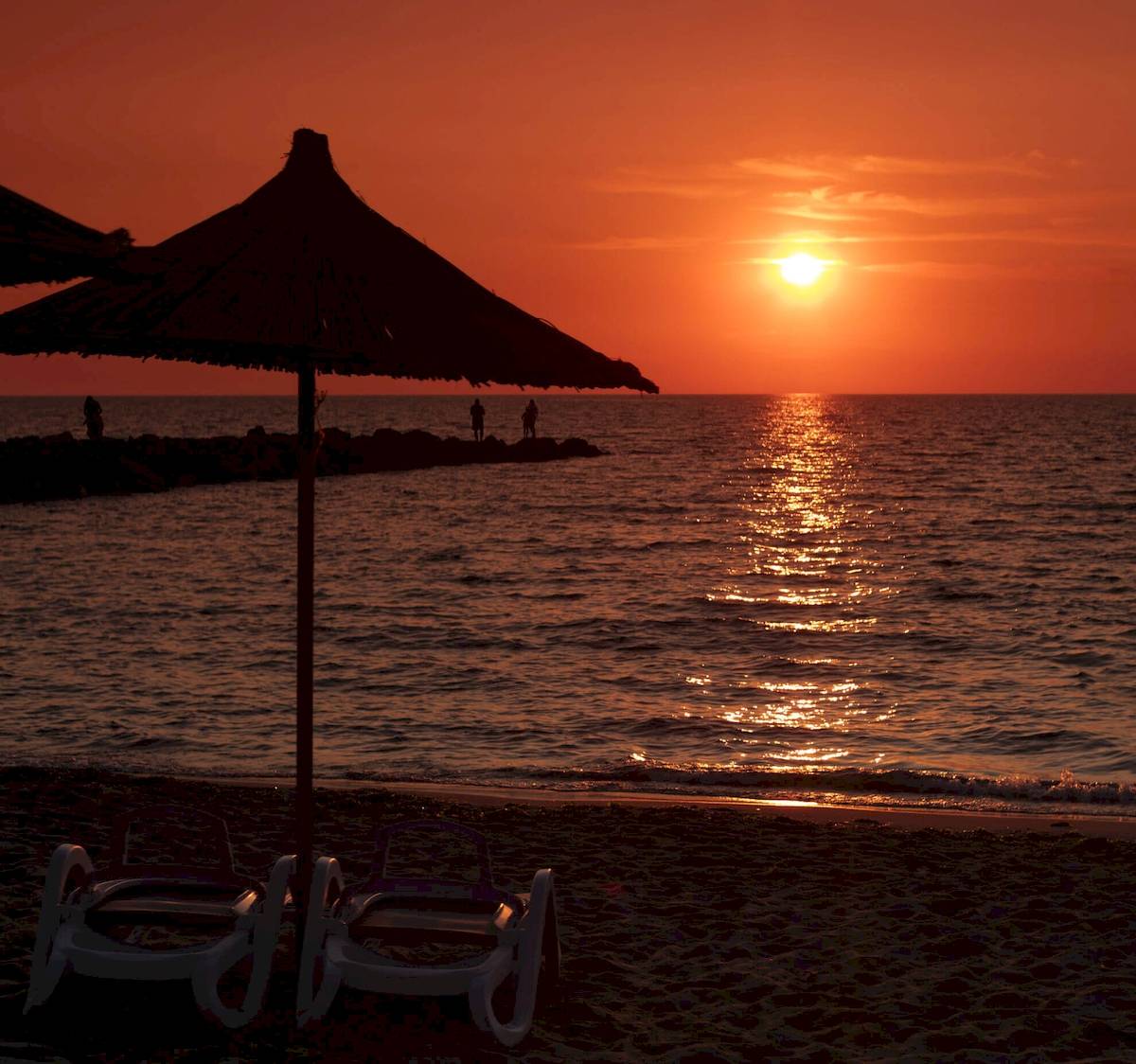 Sonnenuntergang am Strand mit Sonnenschirm und Liegen am Brilliant Hotel & Spa