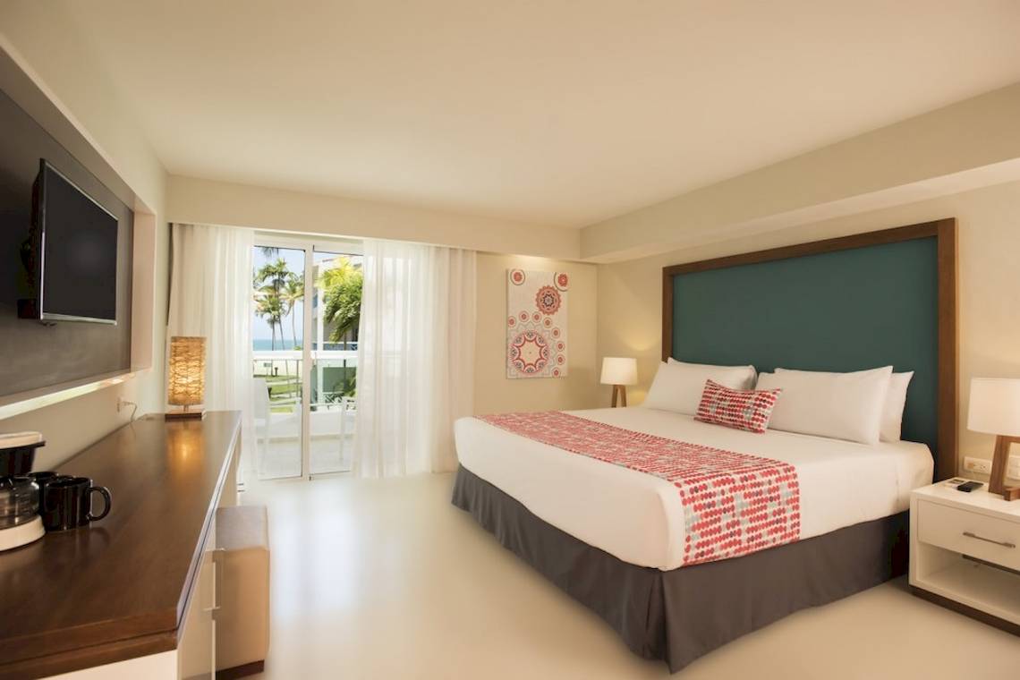 Hotelzimmer im Emotions By Hodelpa Puerto Plata mit Bett, Fernseher und Balkon.