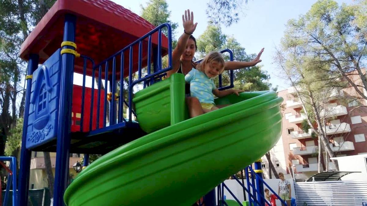 Mutter und Tochter spielen auf einem grünen Rutschenspielplatz im Sandy Beach Resort.
