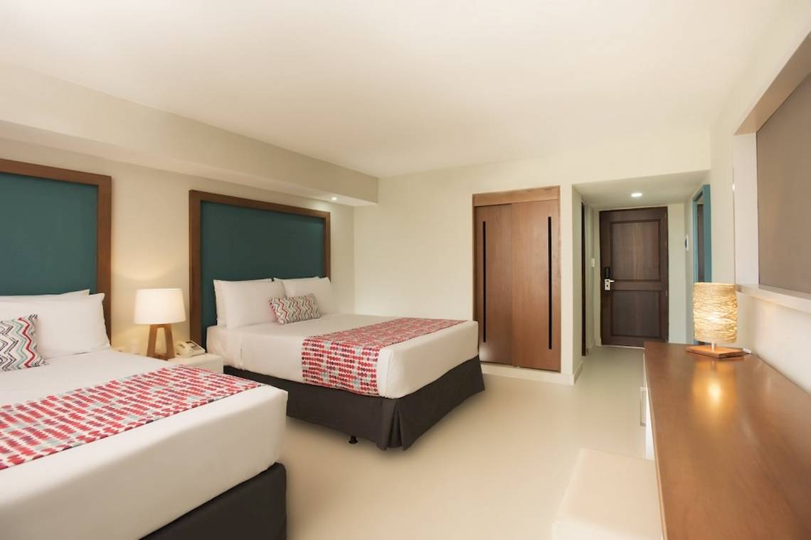 Doppelbett-Zimmer im Emotions By Hodelpa Hotel in Puerto Plata mit zwei Betten, Lampen und Nachttischen.
