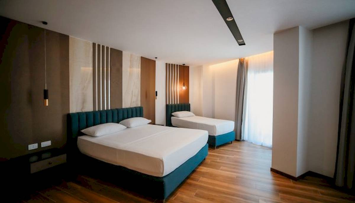 Zwei Betten im Schlafzimmer des Klajdi Resort & SPA, beide mit weißen Laken und Kissen, neben einem Nachttisch.