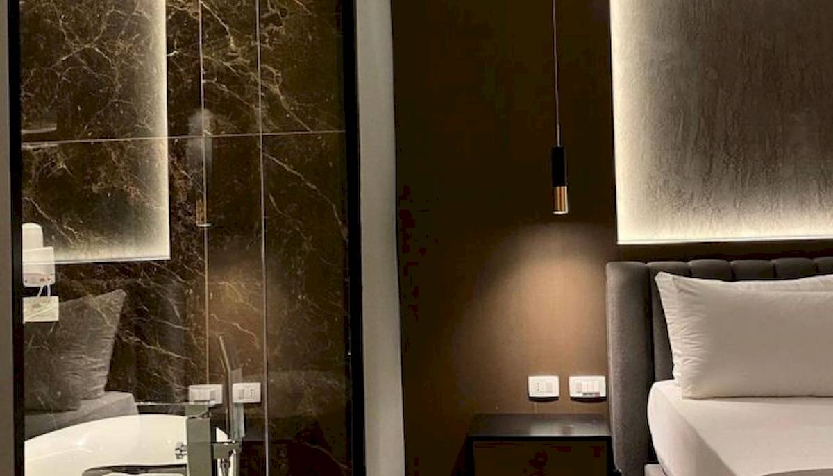Schlafzimmer im Klajdi Resort & SPA mit einem Bett, einem Nachttisch und einem Badezimmerspiegel.
