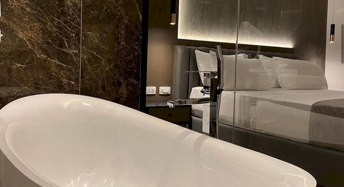 Schlafzimmer im Klajdi Resort & SPA mit Badewanne, Bett und Marmorwand
