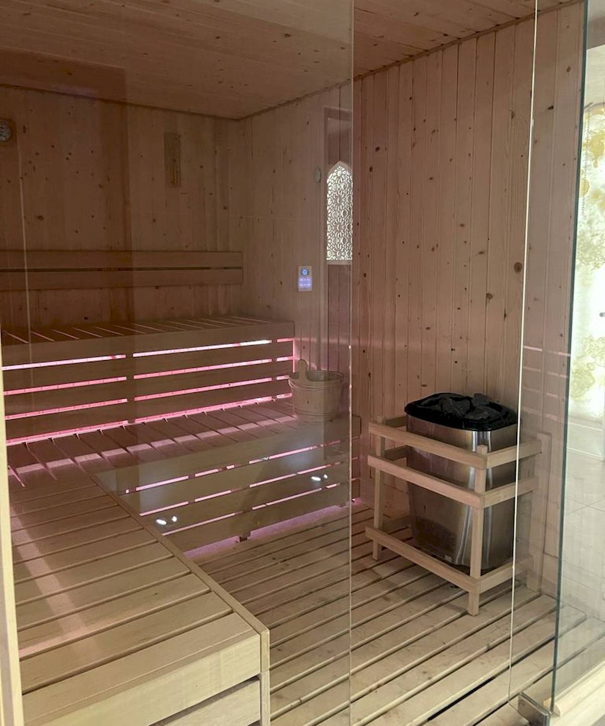 Innenansicht der Sauna im Klajdi Resort mit Holzwänden und Bänken, die mit roten Lichtern beleuchtet sind.