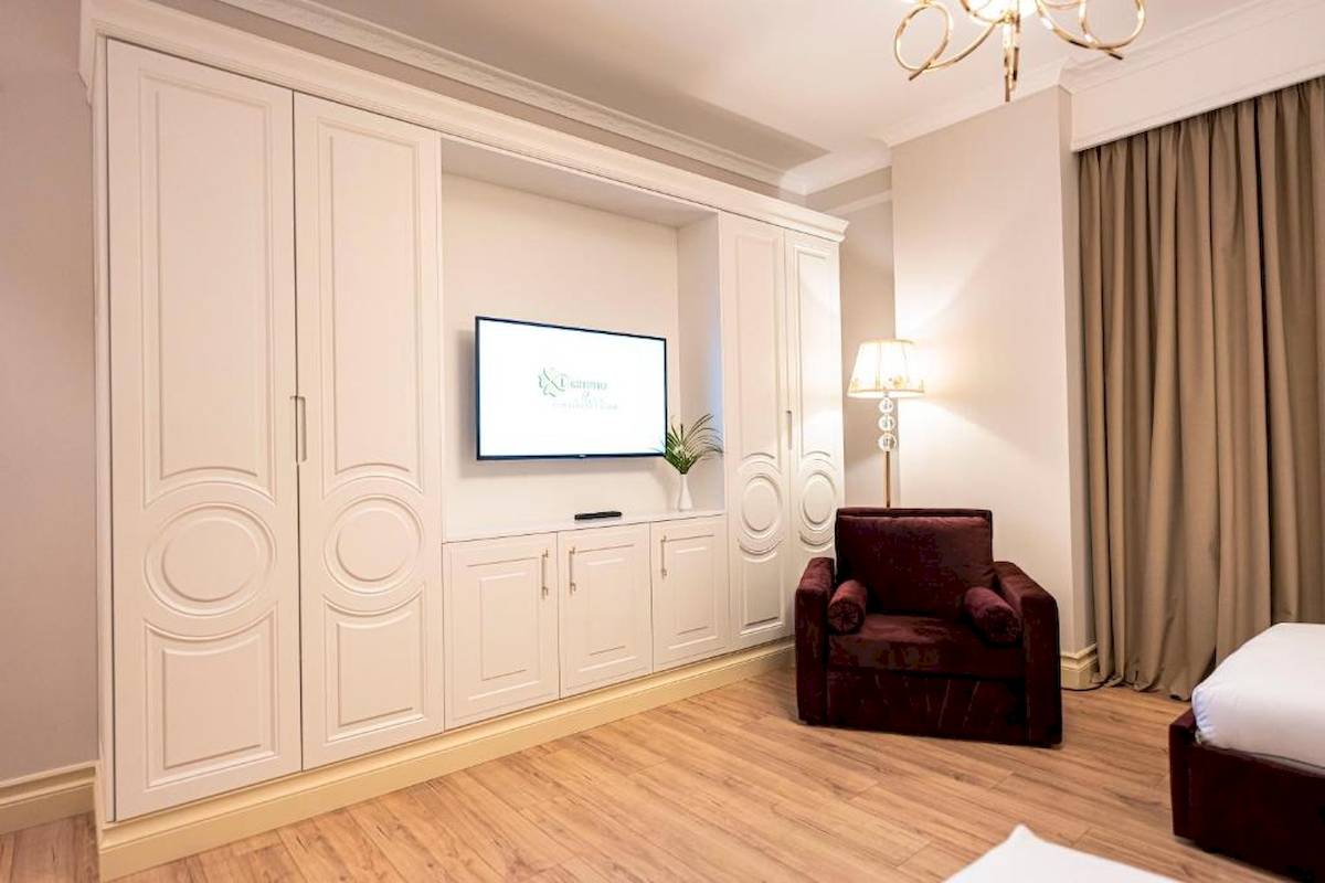 Innenansicht eines Zimmers im Diamma Resort Hotel mit weißem Schrank, Fernseher, Lampe und Bett.