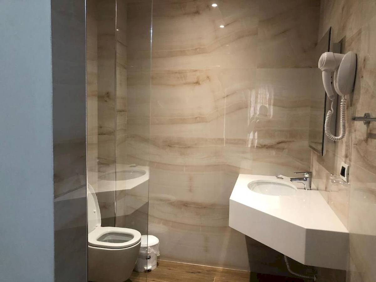 Badezimmer im Vila Mare Hotel mit Glasdusche, Toilette, Waschbecken und Föhn