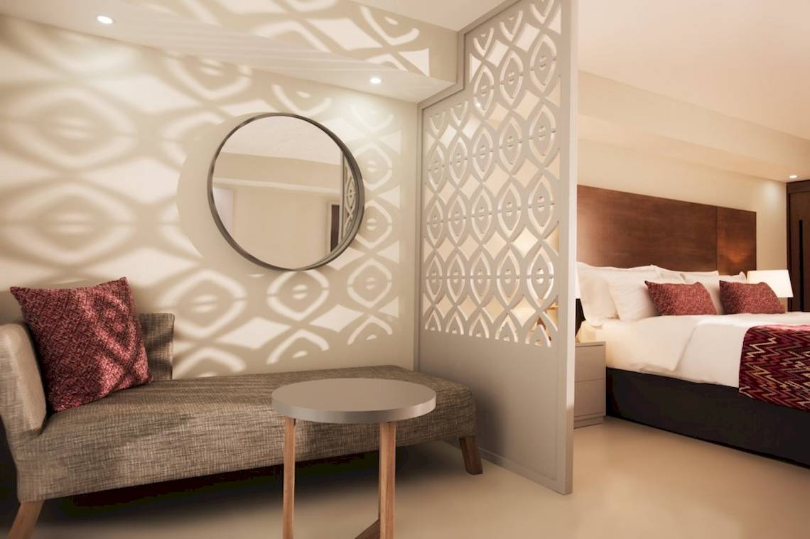 Schlafzimmer im Emotions By Hodelpa Hotel mit Bett, Couch, Tisch und Spiegel.