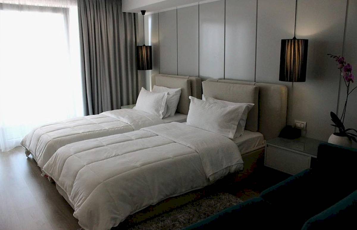 Zwei Betten im Schlafzimmer des Demi Hotels, beide mit weißen Decken und Kissen.
