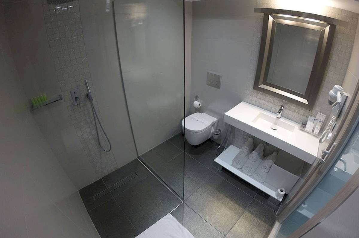 Badezimmer des Demi Hotel mit Dusche, Toilette, Waschbecken und Handtuchtrockner.