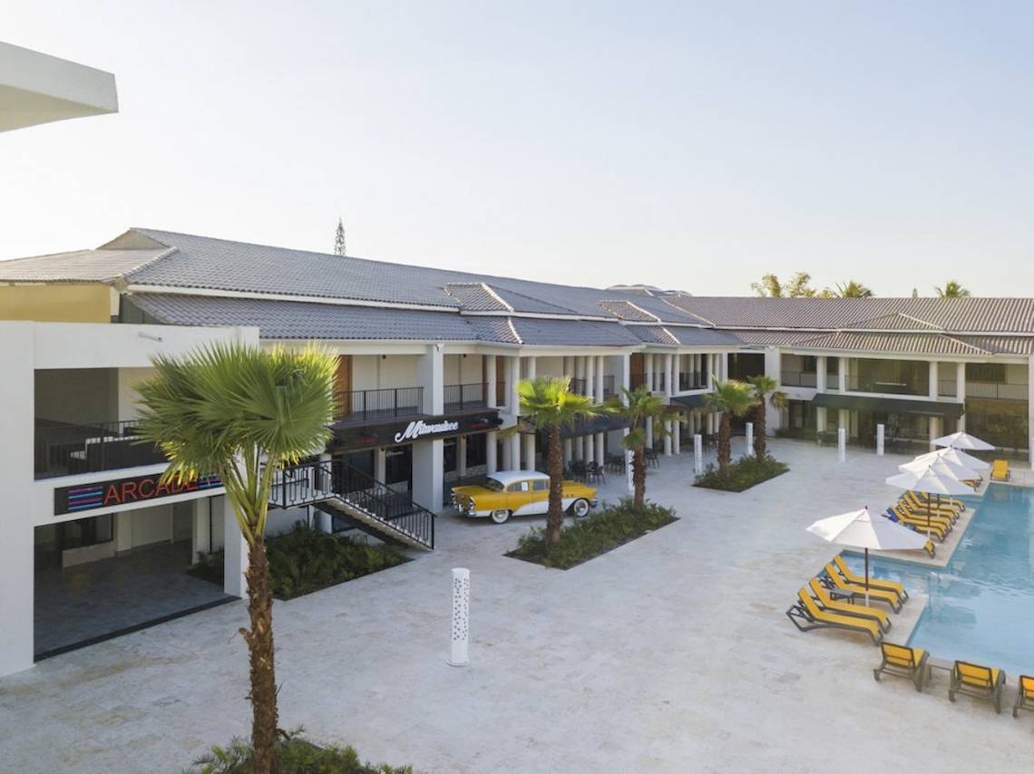 Außenansicht des Emotions By Hodelpa Puerto Plata Hotels mit gelbem Auto und Sonnenliegen