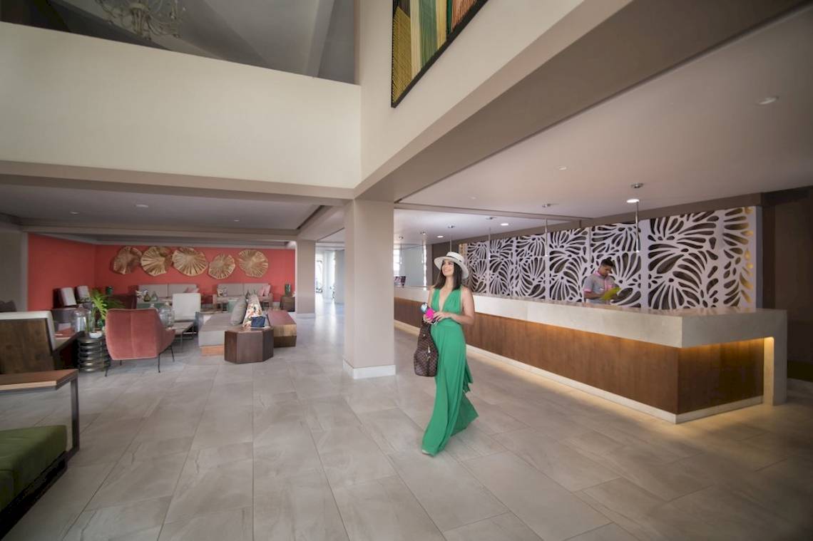 Frau im grünen Kleid geht durch die Lobby des Emotions By Hodelpa Hotels