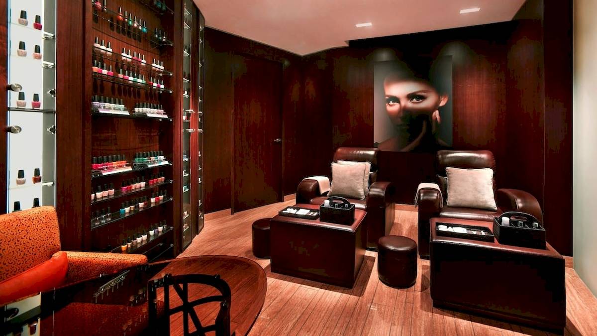 Salonbereich im Grand Hyatt Dubai mit Ledersesseln, Nagellackregalen und einer großen Frau auf der Wand.