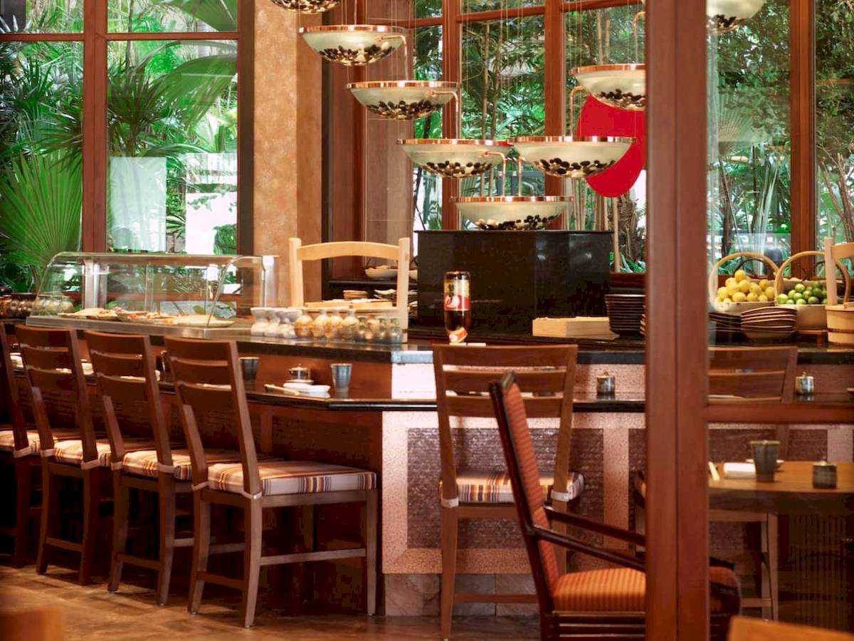 Barbereich im Grand Hyatt Dubai mit Holzmöbeln und grünen Pflanzen im Hintergrund.
