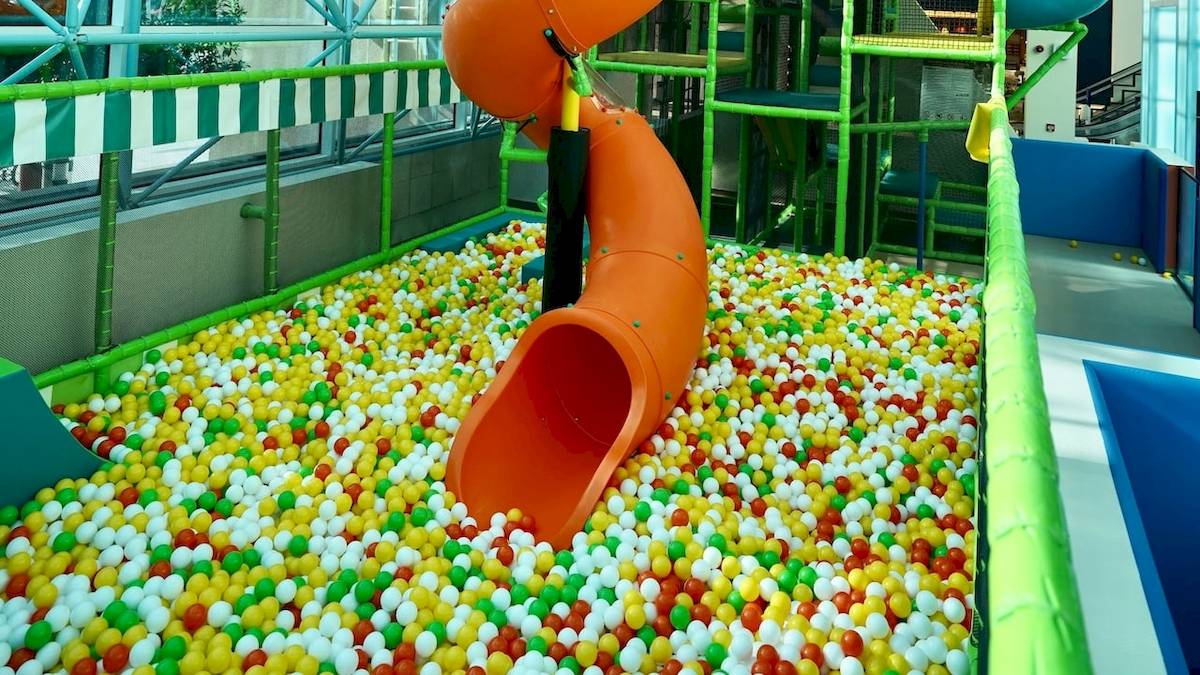 Ein Kinderspielplatz mit einer orangefarbenen Ballenrutsche, umgeben von bunten Bällen.