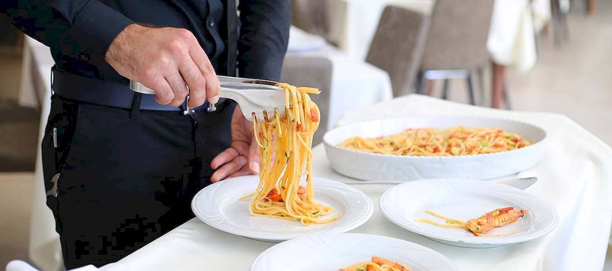 Ein Kellner serviert Spaghetti mit Garnelen im Dyrrah Hotel.