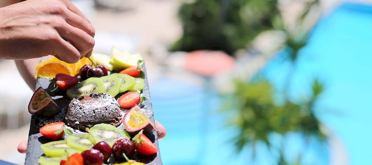 Person, die ein Obstbuffet in der Nähe eines Schwimmbads hält