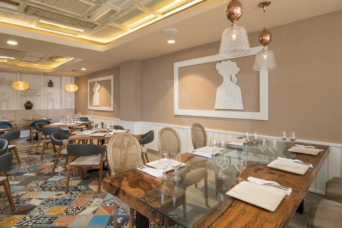 Innenbereich des Restaurants im Emotions By Hodelpa Hotel in Puerto Plata mit Tisch, Stühlen und dekorativen Elementen.
