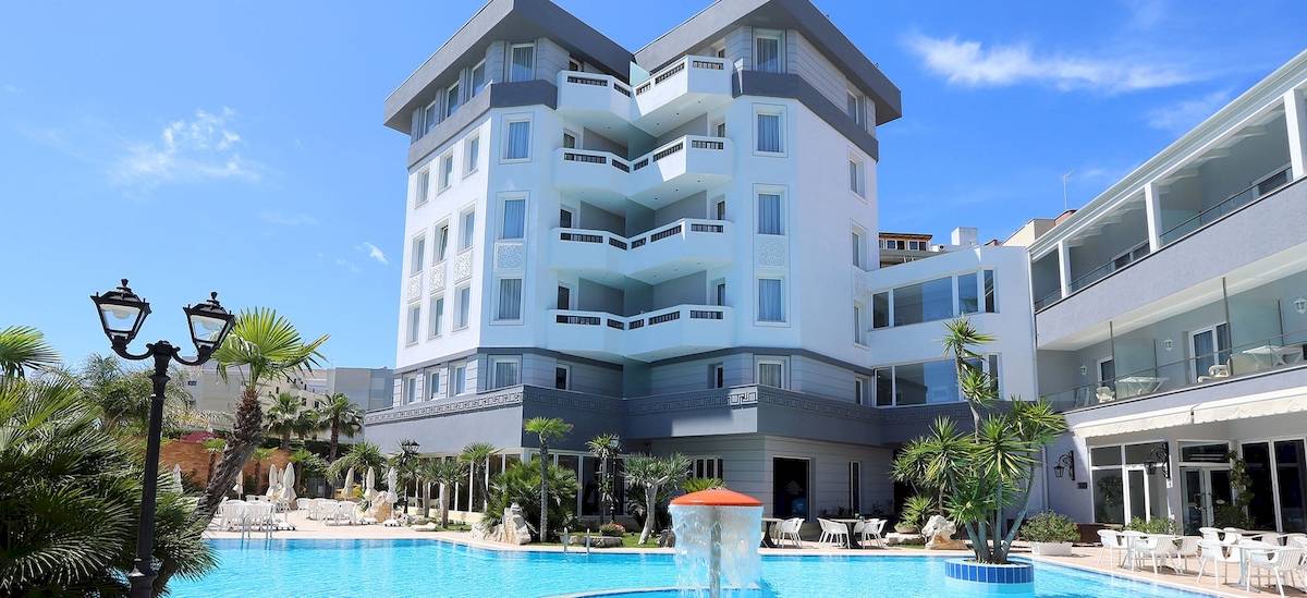 Außenansicht des Dyrrah Hotels mit Pool und mehreren Terrassen und Balkonen.