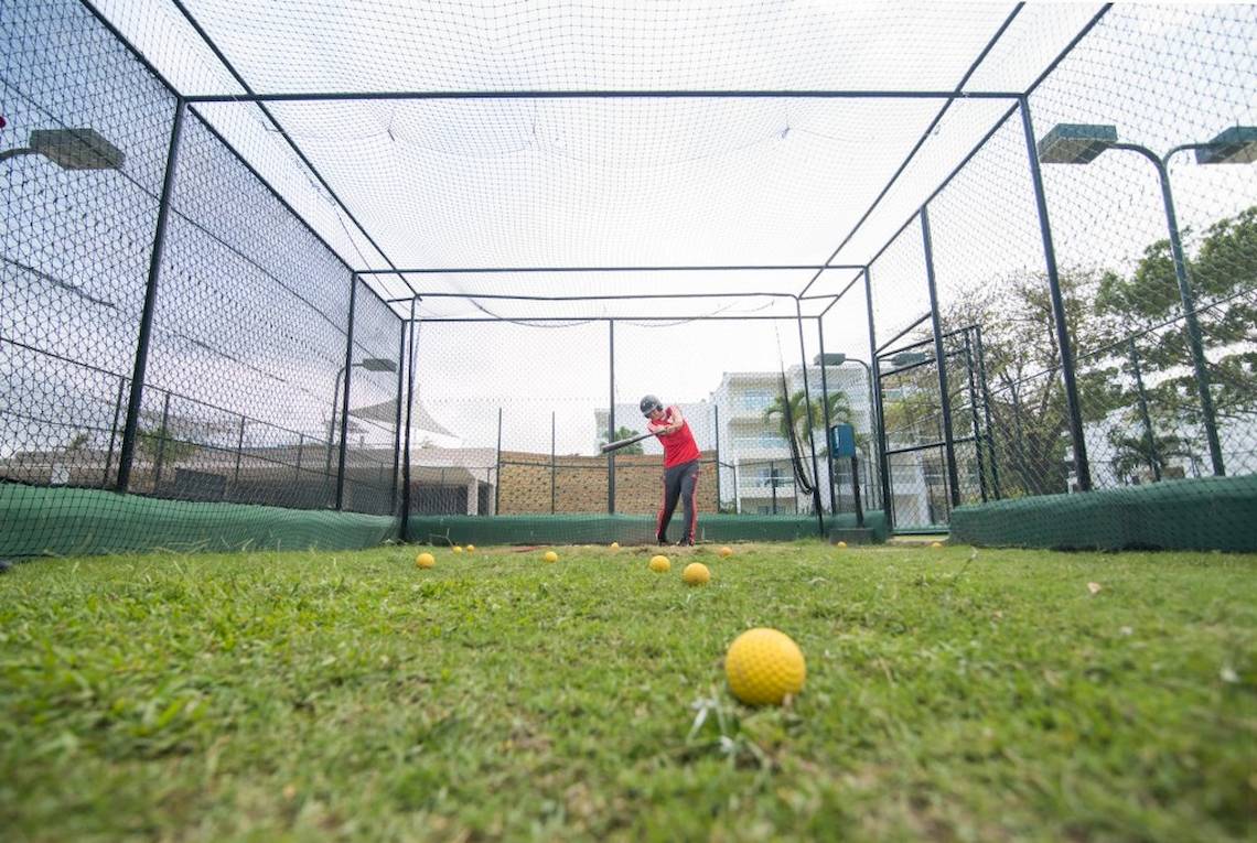 Golftraining unter einem Netz auf einem gepflegten Rasen.