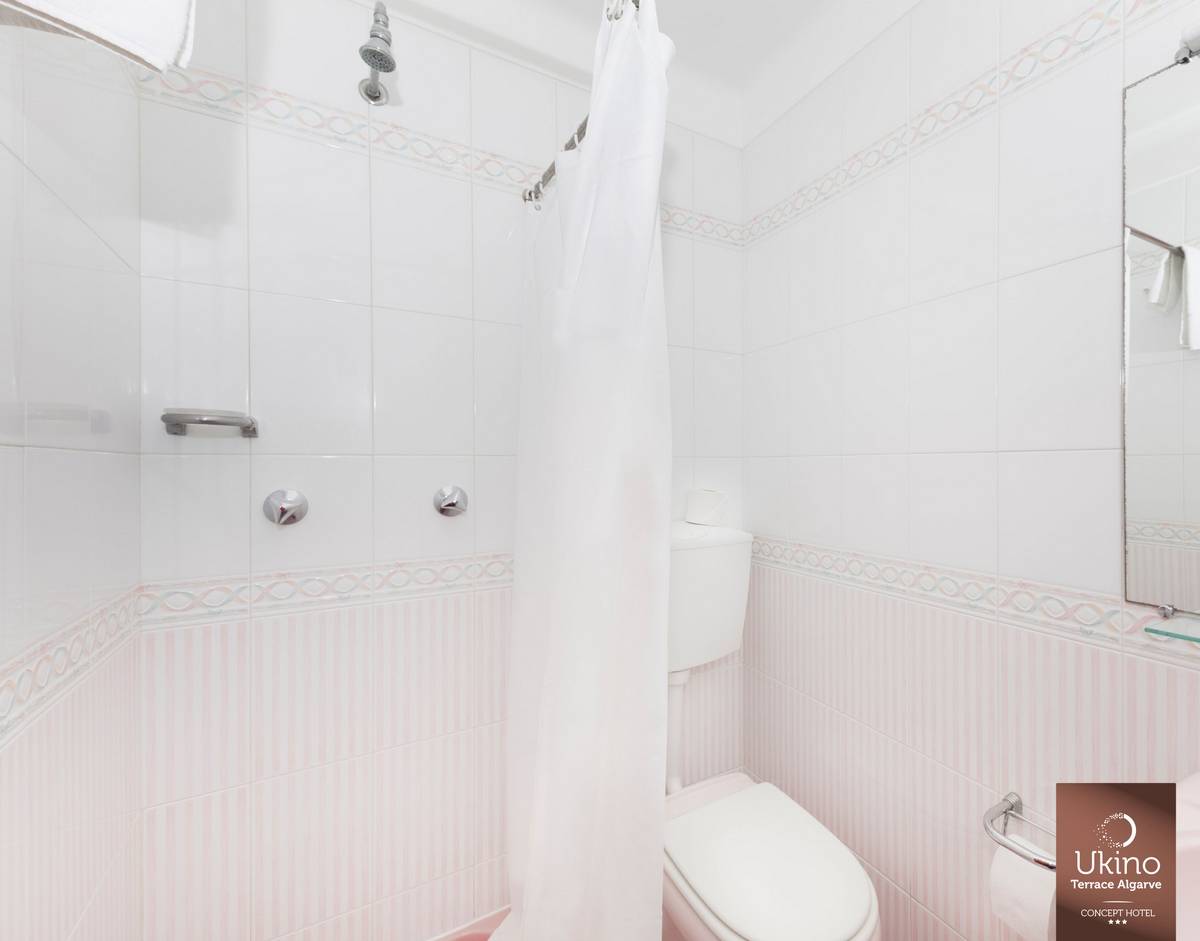 Badezimmer im Ukino Terrace Algarve Hotel mit weißer Dusche und rosa Akzenten.