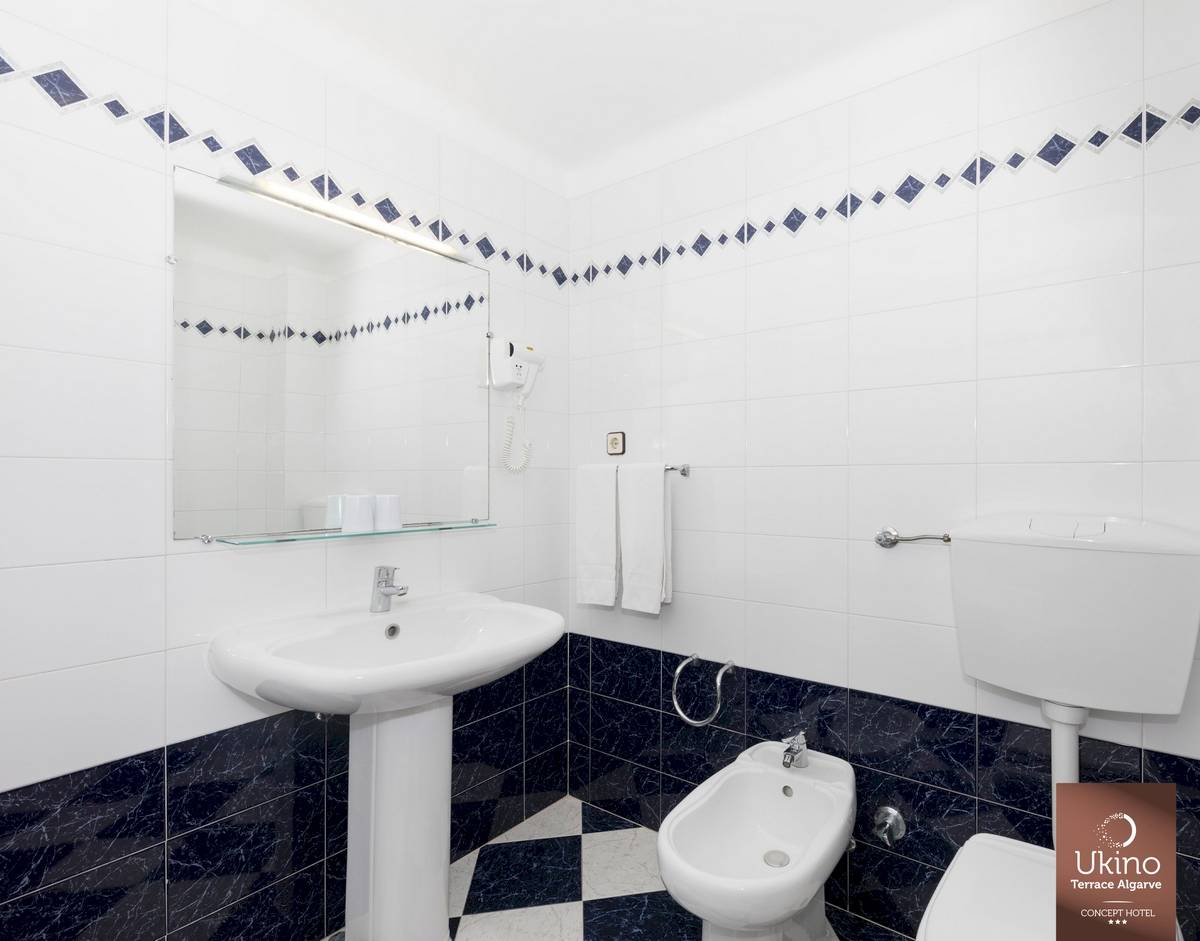 Badezimmer im Ukino Terrace Algarve Hotel mit weißem Waschbecken und Bidet neben einer Toilette.
