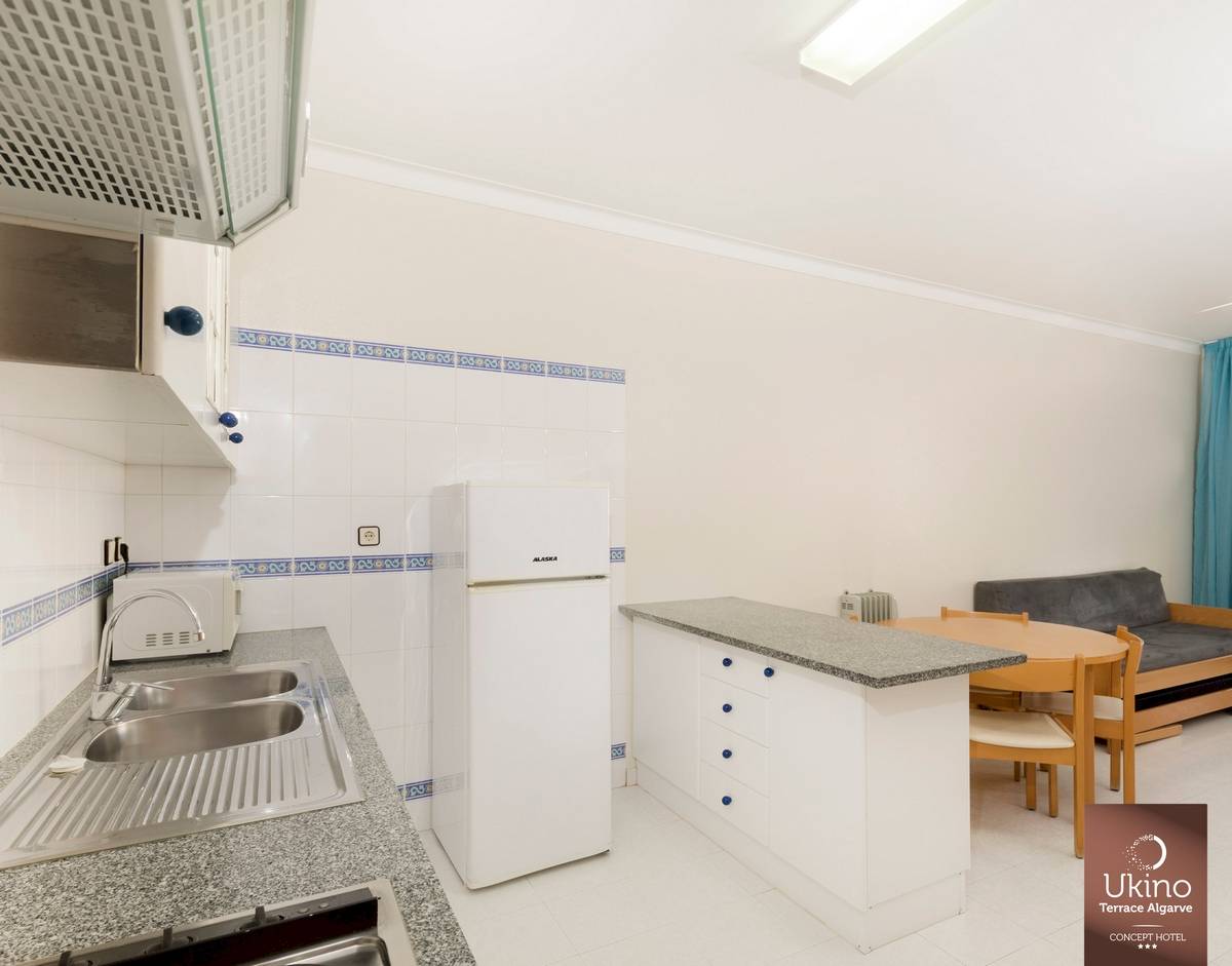 Küche im Ukino Terrace Algarve mit Kühlschrank, Spülbecken und Esstisch.