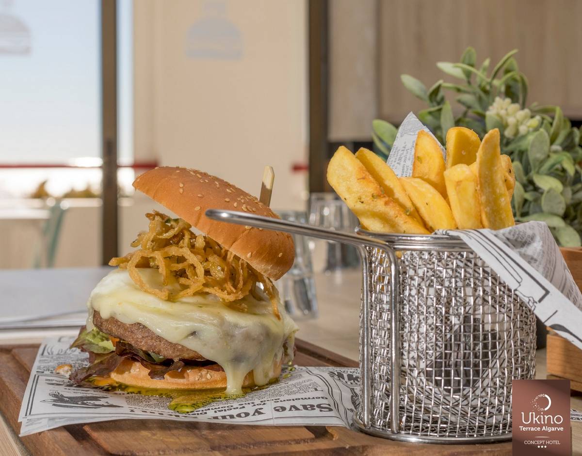 Ein Burger mit Pommes auf einem Tisch im Ukino Terrace Algarve Hotel.