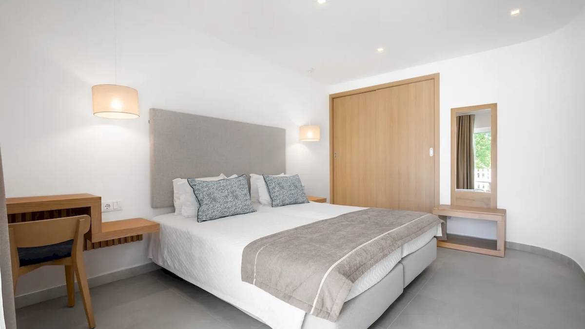 Hotelzimmer im Ancora Park mit weißem Bett, grauen Kissen und heller Einrichtung.