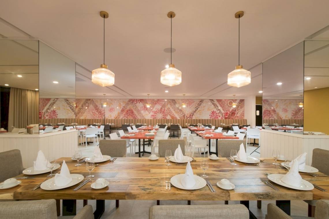 Innenansicht des Restaurants im Emotions By Hodelpa Hotel in Puerto Plata, mit gedeckten Tischen und stilvollen Wanddekorationen.